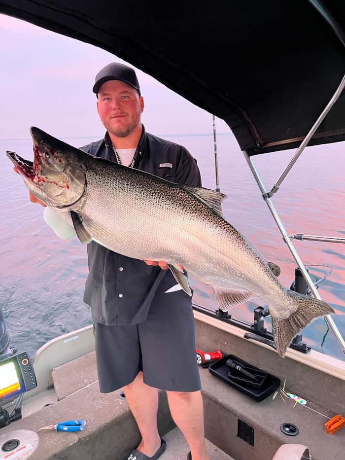 Angler holding a Chinook salmon caught trolling Lake Ontario